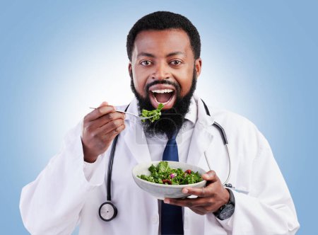 Photo for Doctor studio portrait, black man and salad to lose weight, vegan healthcare diet or healthy food benefits for clean eating. Green lettuce bowl, hungry or African male nutritionist on blue background. - Royalty Free Image