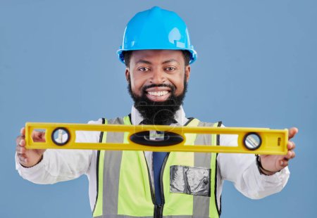 Téléchargez les photos : Heureux homme noir, portrait et architecte avec niveau pour mesurer dans la construction sur un fond de studio bleu. Homme africain, ingénieur ou entrepreneur sourire outil de maintien pour les mesures. - en image libre de droit