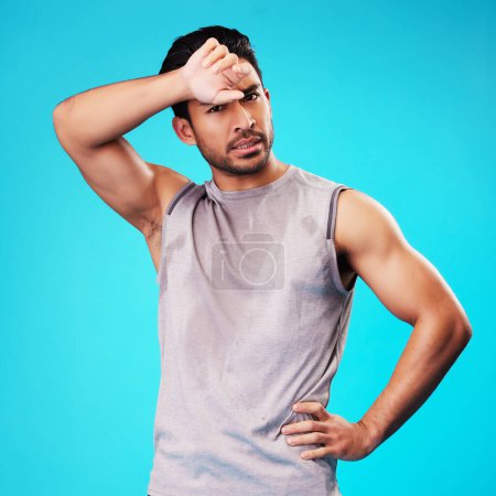 Photo for Portrait, fitness and Asian man tired after exercise in studio isolated on a blue background. Face, serious and athlete with fatigue, wipe sweat and workout for sports, healthy body and wellness. - Royalty Free Image