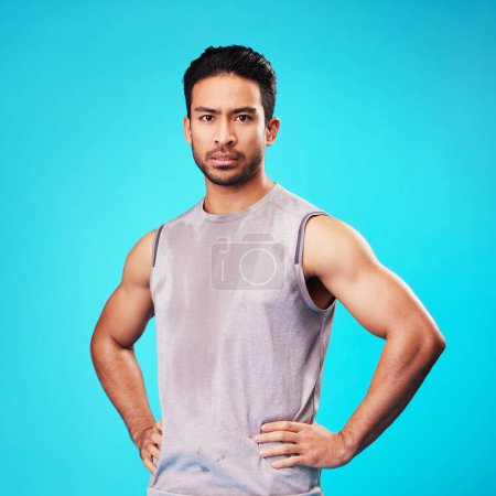 Photo for Portrait, fitness and confident Asian man sweat in studio isolated on a blue background. Face, serious and personal trainer with exercise, workout or sports for healthy body or wellness in Cambodia. - Royalty Free Image