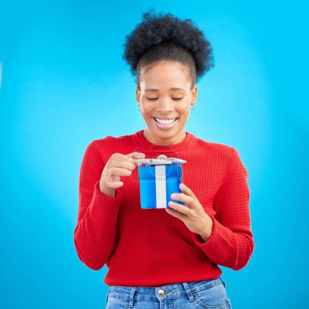 Photo for Smile, birthday and a black woman with a gift on a blue background for happiness or a surprise. Holding, box and a young African girl with a present for a celebration isolated on a studio backdrop. - Royalty Free Image