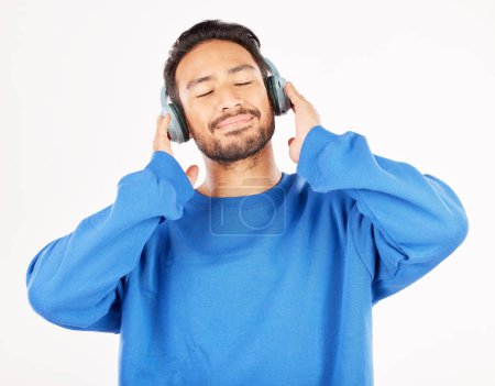 Photo for Asian man, headphones and music in studio, white background and relax while hearing podcast subscription. Happy male model listening to calm audio, streaming sound and radio media with technology. - Royalty Free Image