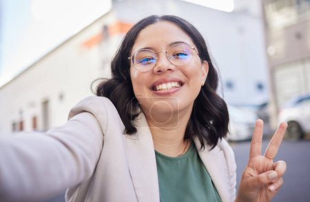 Photo for Business woman, selfie and street with peace sign, smile or glasses for blog, finance career or city. Employee, portrait and happy with icon, memory or photography for profile picture on social media. - Royalty Free Image
