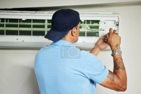 Photo for Man, electrician and ac repair for air conditioner maintenance from the back. Mechanic, technician and engineering tools to fix power of aircon machine, hvac services and check electrical ventilation. - Royalty Free Image
