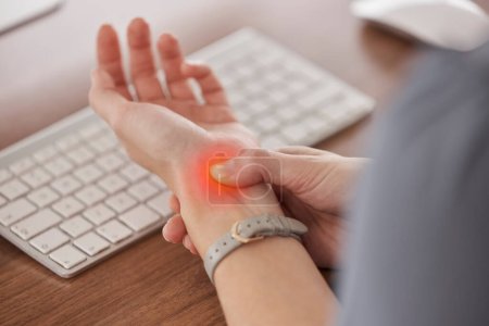 Business person, wrist pain and red injury from osteoporosis, orthopedic joint and laptop typing in office. Closeup, hands and worker with carpal tunnel, fibromyalgia and muscle fatigue at computer.