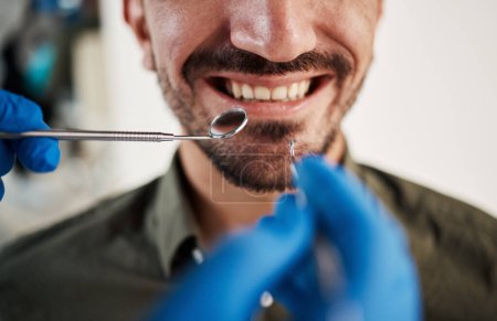 Photo for Smile, man and hands of dentist with tools for dental, healthcare or check in clinic. Tooth wellness, orthodontics and patient with doctor, mirror and excavator for teeth cleaning and medical hygiene. - Royalty Free Image