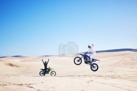 Photo for Bike, winner and motivation with people in the desert for fitness or adrenaline while training. Motorcycle, support and celebration with athlete friends cheering a jump in Dubai for energy or freedom. - Royalty Free Image