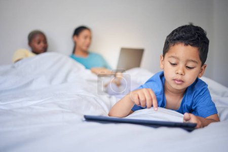 Photo for Children, tablet and education with a family in bed in the morning to relax together at home. Kids, technology and child development with a little boy in the bedroom to play a fun online game. - Royalty Free Image