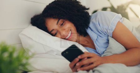 Foto de Teléfono de texto, mujer feliz y la cama de una joven mujer mensajes de texto en una aplicación de redes sociales por la mañana. Wifi, redes web y felicidad de un joven con una sonrisa en una casa leyendo un mensaje. - Imagen libre de derechos