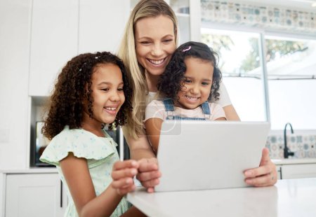 Blended family, adoption and a mother with her children on a tablet in the kitchen for education or learning. Children, diversity and study with woman teaching her girl kids in their home together.