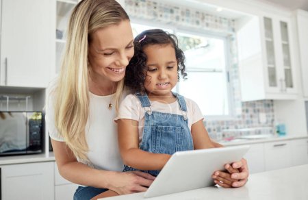 Blended family, adoption and a mother with her daughter on a tablet in the kitchen for education or study. Children, diversity and learning with woman teaching her girl kid in their home together.