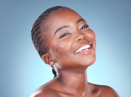 Téléchargez les photos : Visage de femme noire heureuse pour le maquillage, la beauté et les cosmétiques en studio pour le bien-être, la santé et le spa. Salon esthétique, dermatologie et personne africaine avec soin de la peau, du visage et lueur sur fond bleu. - en image libre de droit