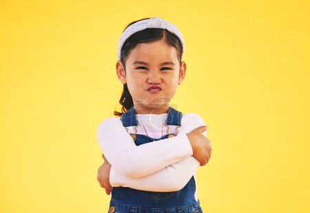 Photo for Portrait, arms crossed and angry girl child in studio with bad, attitude or behavior problem on yellow background. Frown, face and asian kid with body language for no, frustrated or tantrum emoji. - Royalty Free Image