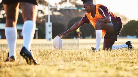 Téléchargez les photos : Rugby ball, kick et sport avec maintien du soutien, de l'exercice et de la compétition avec l'entraînement des athlètes. Pratique sur le terrain, homme noir et cible sur herbe avec fitness et entraînement en équipe en plein air pour le travail d'équipe. - en image libre de droit