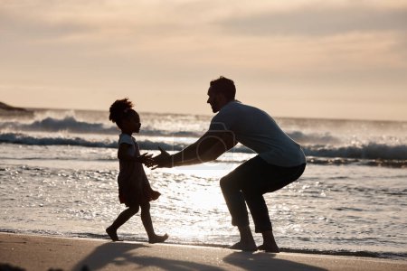 Photo for Sunset, beach and silhouette of father with girl child in nature, bond and playing, freedom and enjoying summer vacation. Ocean, shadow and kid hug parent at sea with love, care and embrace in Bali. - Royalty Free Image