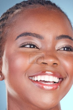 Téléchargez les photos : Visage de femme noire pour soins de la peau, beauté et sourire sur fond bleu pour le bien-être, la santé et le spa. Salon esthétique, dermatologie et gros plan de la personne heureuse en studio avec cosmétiques, maquillage et lueur. - en image libre de droit