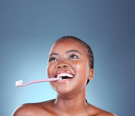 Photo for Black woman, face or toothbrush for cleaning teeth on isolated blue background, studio or mockup space. Smile, model or dental toothpaste for gum wellness, breath or mouth hygiene in grooming routine. - Royalty Free Image