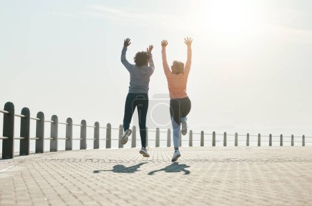 Foto de Fitness, salto y libertad con amigos en la playa para la celebración, motivación y entrenamiento. Cardio, entrenamiento y salud con mujeres maduras en la naturaleza para correr, energía y objetivos de ejercicio juntos. - Imagen libre de derechos