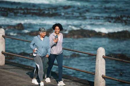 Photo for Fitness, walking and woman and senior mother by ocean for healthy body, wellness and cardio on promenade. Sports, happy and female people on boardwalk for exercise, marathon training and workout. - Royalty Free Image