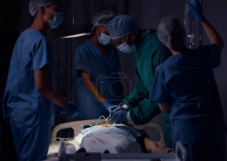 Photo for Hospital surgery, teamwork and surgeon operation, emergency service or helping patient in healthcare dark room. Clinic support, operating theatre or doctors doing medical procedure on client at night. - Royalty Free Image