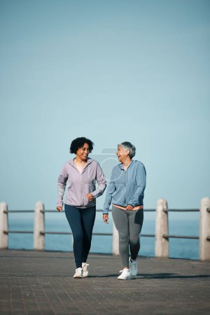 Photo for Exercise, walking and senior women by ocean for healthy body, wellness and cardio on promenade. Sports, friends and happy female people in conversation on boardwalk for fitness, training and workout. - Royalty Free Image
