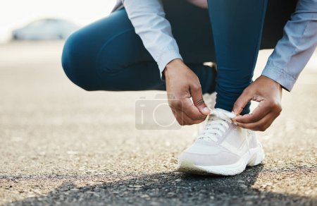 Foto de Deportes, primer plano y mujer corbata zapatos al aire libre en la carretera para hacer ejercicio en la ciudad. Fitness, salud y zoom de atleta femenina atándose los cordones para el ejercicio cardiovascular para el entrenamiento de carrera o maratón - Imagen libre de derechos