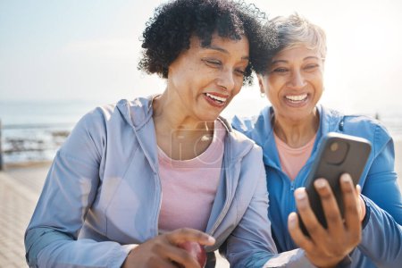 Photo for Senior women, phone and social media in nature for a chat, notification or a funny meme. Happy, reading online and elderly friends by the sea with a mobile app for communication or internet memory. - Royalty Free Image