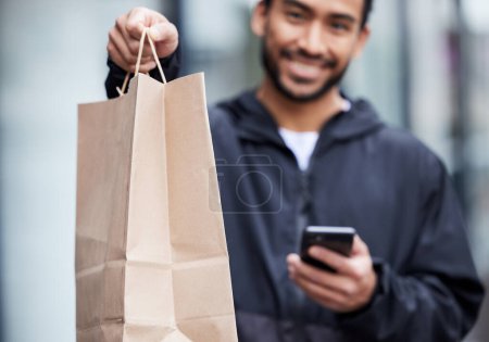 Photo for Courier man, giving paper bag and portrait with phone, smile and delivery service in supply chain job. Young logistics worker, package and hand with smartphone, product and e commerce in metro cbd. - Royalty Free Image