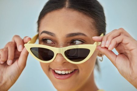 Photo for Smile, sunglasses and young woman in a studio with a casual, stylish and cool eyewear. Happy, excited and female model with trendy gen z style and fashion accessory isolated by a blue background - Royalty Free Image