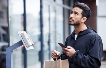 Photo for Courier man, paper bag and city with phone, typing and delivery app with search in supply chain job. Young logistics worker, package and thinking with smartphone, product and ecommerce in metro cbd. - Royalty Free Image