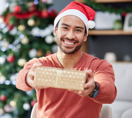 Photo for Christmas, portrait and asian man with gift giving in his home for celebration, fun and holiday with a smile. Happy, face and Japanese male with present box offer in a living room for festive event. - Royalty Free Image