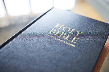 Photo for Closeup, bible book and home for faith, studying religion and mindfulness with holy spiritual scripture. Christian literature, morals and ethics for knowledge, language and worship for Jesus Christ. - Royalty Free Image