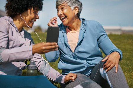 Photo for Music, fitness and senior friends laughing on the grass outdoor taking a break from their workout routine. Exercise, training and funny with elderly people streaming audio on a field for wellness. - Royalty Free Image