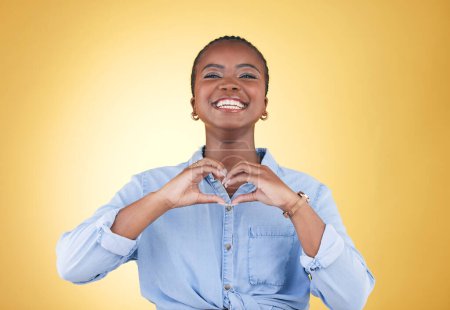 Téléchargez les photos : Portrait, mains de coeur et femme noire, sourire et studio isolé sur fond jaune. Visage, signe d'amour et heureux Africain dans la bonté, le soin et l'empathie, le soutien et la confiance, la romance ou la solidarité. - en image libre de droit