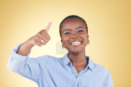 Foto de Mujer negra, retrato y pulgares hacia arriba, retroalimentación y apoyo con sonrisa aislada sobre fondo amarillo. Feliz, acuerdo y gesto de mano con crítica positiva, sí y como emoji con éxito en un estudio. - Imagen libre de derechos