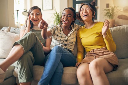 Photo for Happy, friends and women watching tv on a sofa laughing, bond and relax in their home on the weekend. Television, movie and people with diversity in living room for streaming, film or comedy in house. - Royalty Free Image