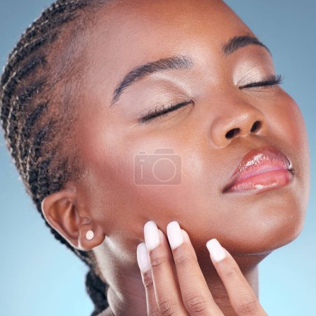 Téléchargez les photos : Beauté, peau et une femme noire avec la main sur le visage pour la dermatologie, maquillage naturel et manucure. Gros plan de la personne africaine sur un fond de studio avec des cosmétiques et de l'éclat du visage, brillance ou toucher doux. - en image libre de droit