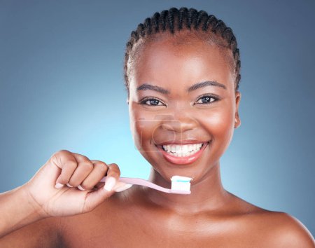Foto de Mujer negra feliz, retrato y cepillo de dientes en la limpieza de dientes o cuidado dental contra un fondo de estudio. Rostro de mujer africana con gran sonrisa en blanqueamiento dental, higiene oral o bucal y de las encías. - Imagen libre de derechos