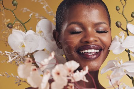 Photo for Black woman, flowers and beauty with smile, makeup and natural cosmetics isolated on studio background. African model, orchid and nature, sustainable skincare with eyes closed, facial and glow. - Royalty Free Image