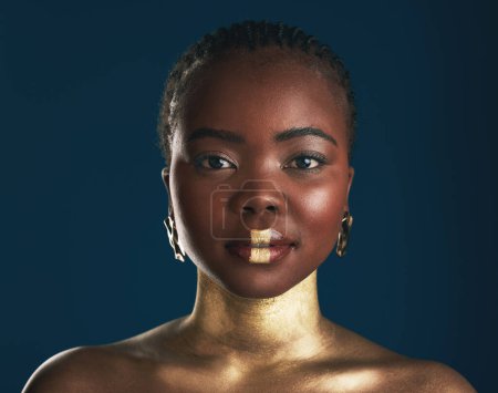 Téléchargez les photos : Maquillage doré, portrait en studio ou femme noire avec art créatif, peinture cosmétique faciale et rouge à lèvres. Culture africaine, éclat du visage et personne avec design de beauté, bien-être ou créativité sur fond bleu. - en image libre de droit