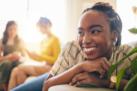 Foto de Mujer feliz, pensante y negra relajándose en la sala de estar con sus amigos en el apartamento moderno. Felicidad, mujer africana positiva y joven soñando y sentándose en el salón para descansar en casa - Imagen libre de derechos