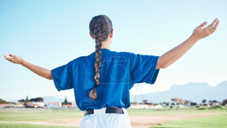 Photo for Woman, arms raised and winner with cheers, softball and sports with athlete on outdoor pitch and back view. Pray, hope and freedom, celebration and exercise, baseball player and winning competition. - Royalty Free Image