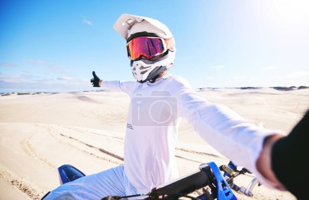 Foto de Selfie, motocicleta y hombre en la aventura del desierto, la naturaleza y los deportes al aire libre en el espacio de la maqueta. Bicicleta, casco y persona toman fotos en la arena para las redes sociales, el transporte y los viajes fuera de carretera en Marruecos. - Imagen libre de derechos