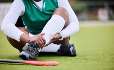 Photo for Hockey, pain and leg injury by woman player on a field with problem, joint or muscle crisis in sport. Hand holding, ankle and athlete with emergency, inflammation or fitness accident from training. - Royalty Free Image