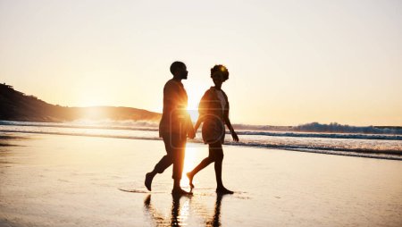 Photo for Beach sunset, silhouette and couple walking, holding hands and enjoy romantic conversation, freedom and travel holiday. Love, sea and dark shadow of people bonding, talking and relax on tropical date. - Royalty Free Image
