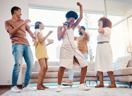 Photo for Happy, party and people singing karaoke in the living room with a microphone to music, playlist or radio. Entertainment, diversity and young friends dancing, bonding and having fun together at home - Royalty Free Image