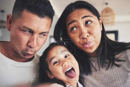 Photo for Selfie, silly and portrait of girl with her parents bonding in the living room of their home. Goofy, happy and child taking a picture with her mother and father with funny faces at their family house. - Royalty Free Image