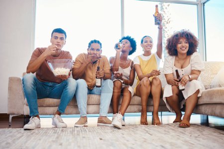 Téléchargez les photos : Popcorn, bière et amis regarder la télévision en streaming dans le salon à la maison, coller et s'amuser ensemble. Nourriture, personnes heureuses et groupe à la télévision pour boire de l'alcool, regarder des films et des films pour se détendre sur le canapé - en image libre de droit