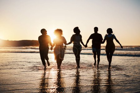 Photo for Holding hands, silhouette and friends at the beach with freedom, fun and bonding at sunset. Ocean, shadow and group of people at the sea for travel, adventure and journey in sea trip in Los Angeles. - Royalty Free Image