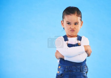 Photo for Angry, child and arms crossed with tantrum in studio with mockup space. Kid, young girl and frustrated with cross frown and pout with a problem and mad attitude with blue background and grumpy. - Royalty Free Image